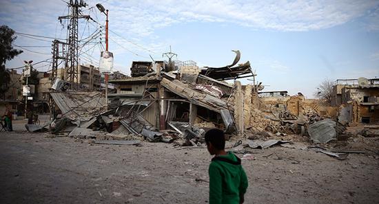 一名叙利亚民众经过冲突后的废墟(图:路透)